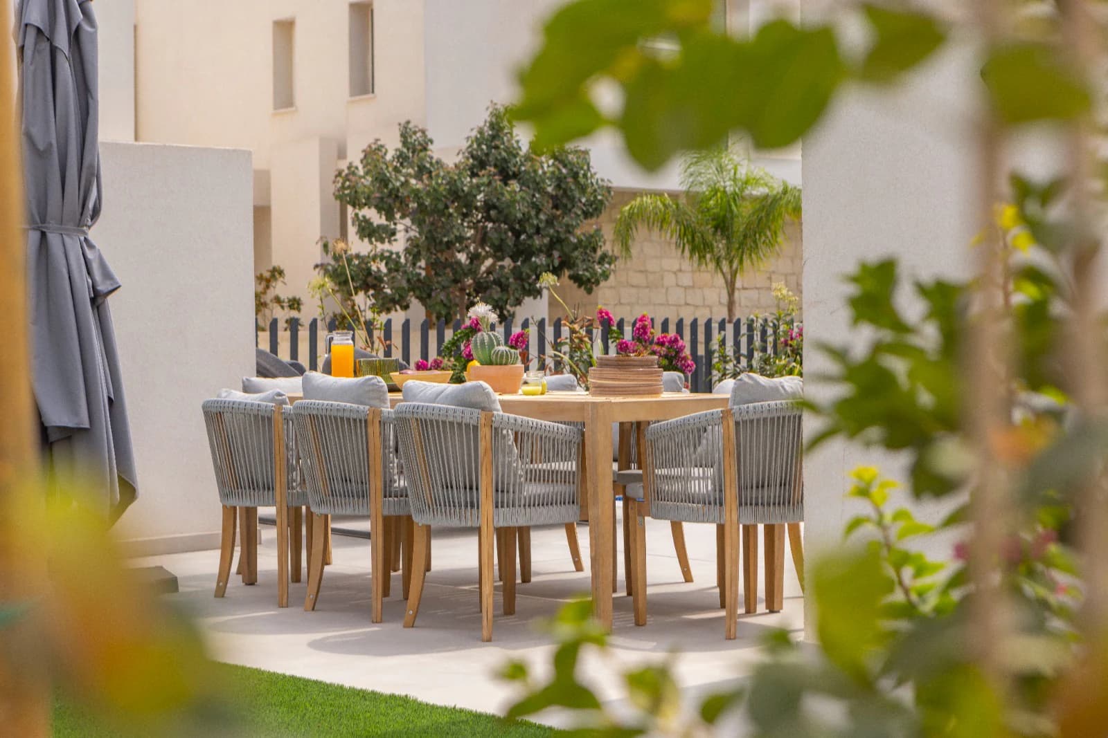 The outdoor dining table seen through foliage in the morning.