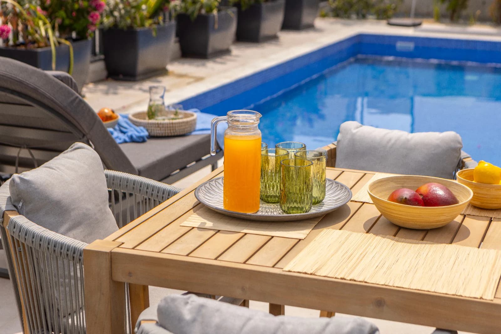 Juice and fruit laid out on a poolside table.