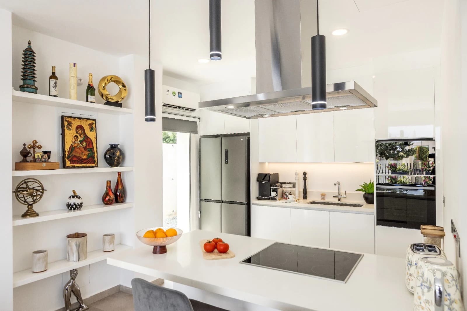 The kitchen island and induction hob, with the display shelving niche alongside and the galley run behind.