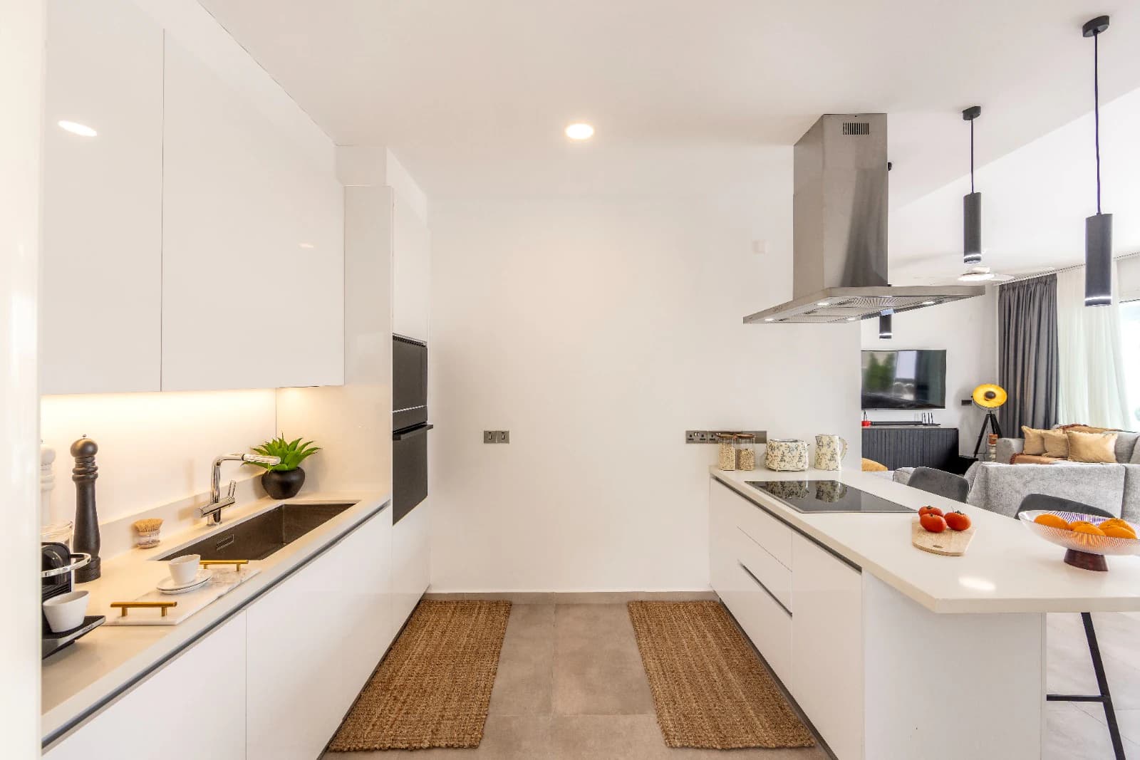 The galley kitchen run with its sink and ovens, opening at the far end onto the island and the living room.