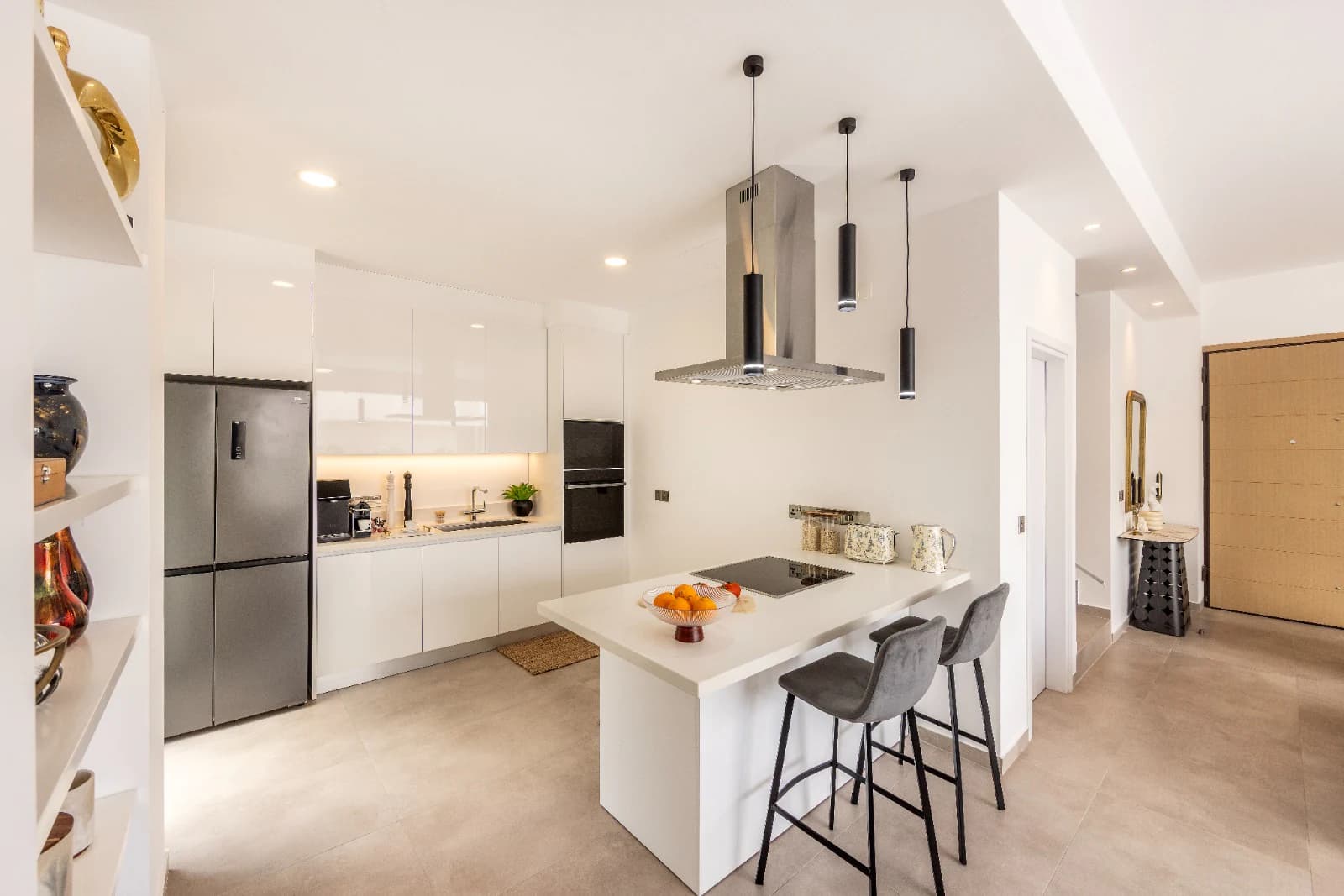 The kitchen island and breakfast stools, with the entrance hall and front door beyond.